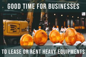 Several orange construction warning lights are lined up in front of heavy equipment at a construction site. Text over the image reads: Good time for businesses to lease, rent, or explore financing for heavy equipment.