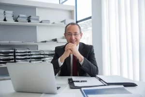 a man sitting at a desk with his hands together