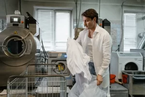 a man in a white shirt holding a plastic bag in a laundry room