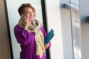 A woman in a purple dress discusses Merchant Cash Advance Rates while talking on her cell phone.