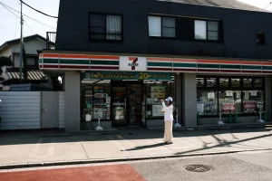 Person standing outside a 7-Eleven convenience store in Japan taking a photo