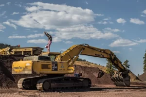 Person performing a handstand on a Komatsu excavator at a construction site