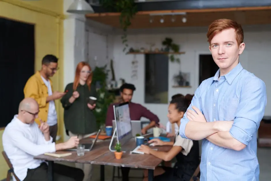 Confident young professional standing in front of a diverse team working in a modern office environment