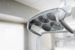 Close-up of a modern dental or medical overhead examination light with multiple round bulbs, in a clean, bright clinical setting.
