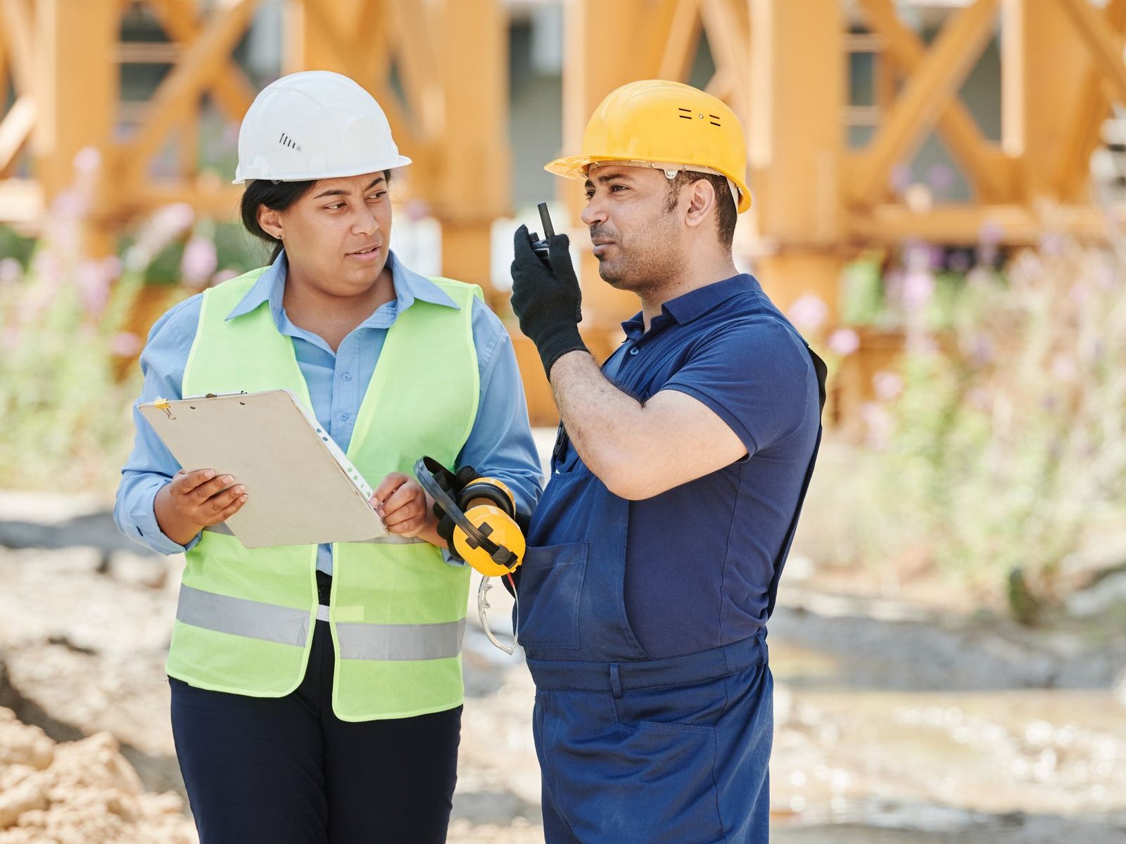 Contractor with a clipboard talking with her foreman on a job site - invoice factoring for contractors