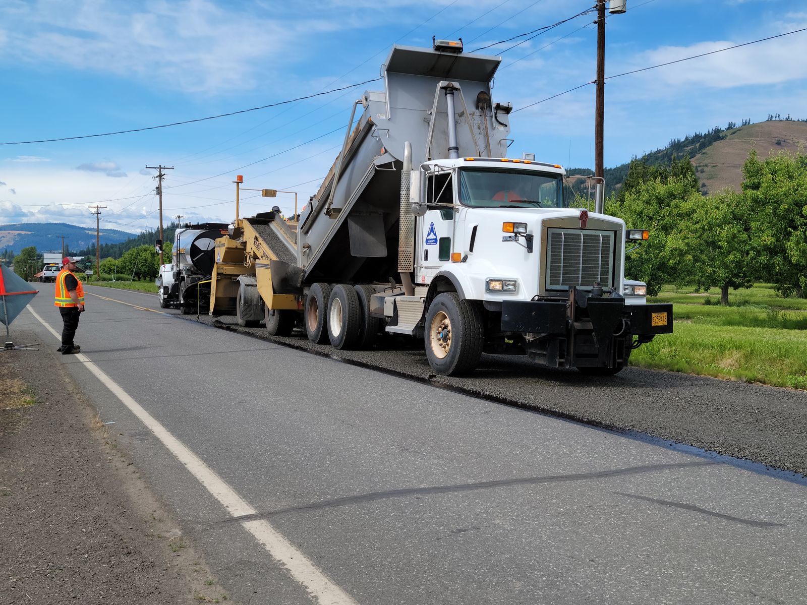 Dump truck feeding an asphalt paver on a road paving job