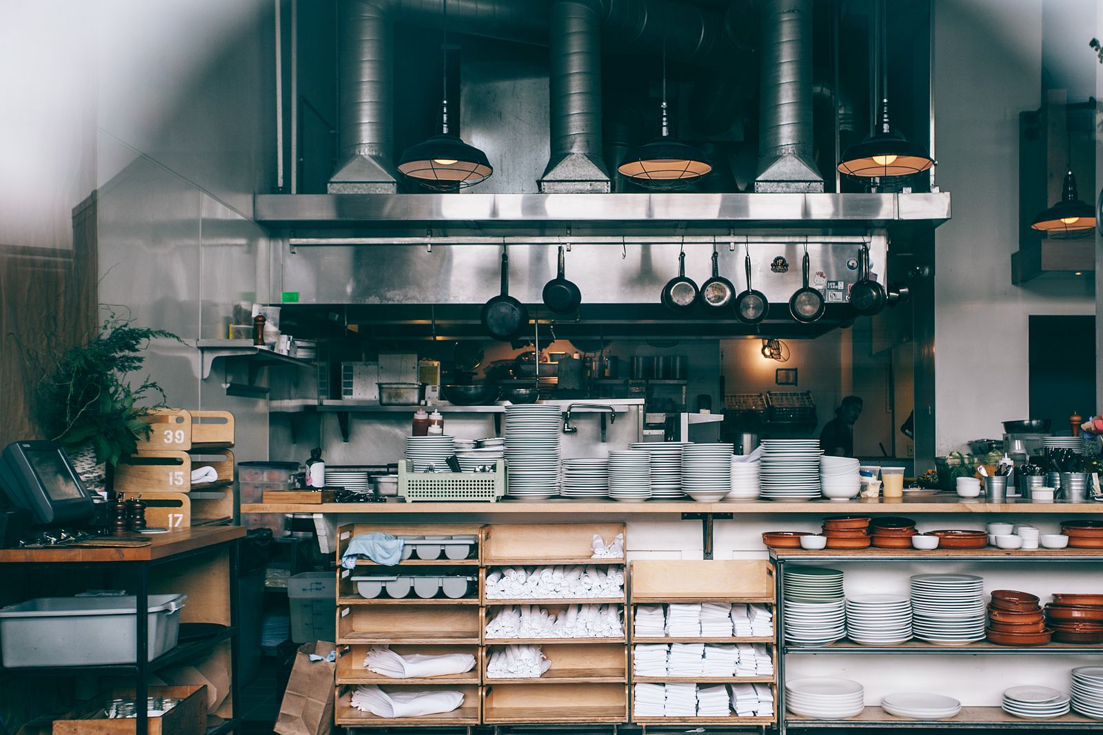 Commercial restaurant kitchen with stainless hoods, prep line and plate storage, equipment covered by kitchen equipment financing