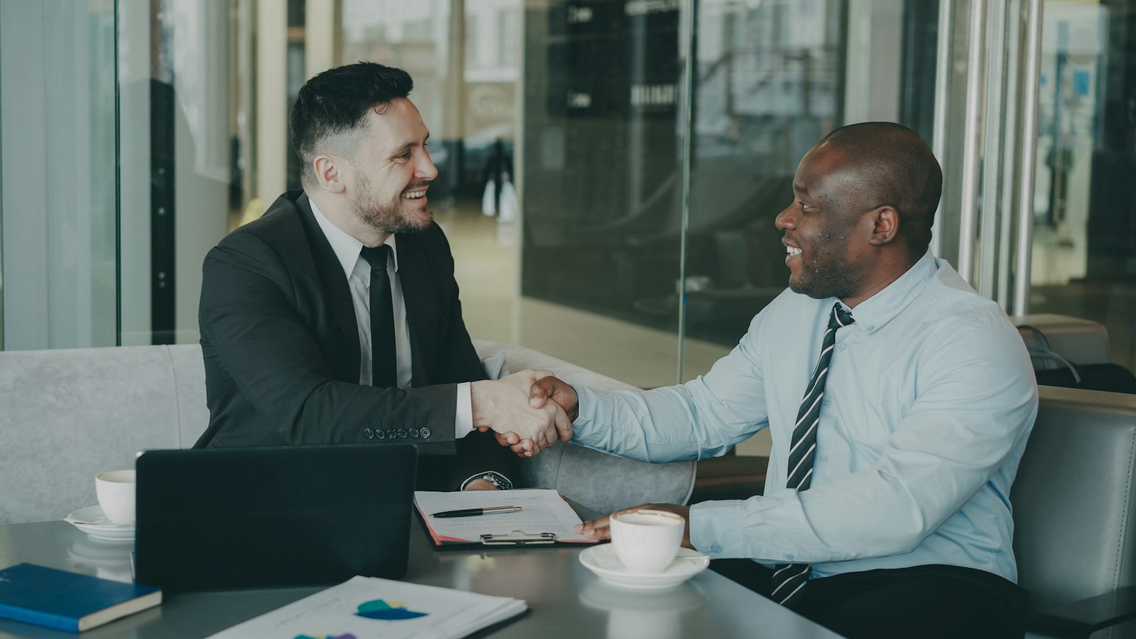 Business owner shaking hands with an equipment loan broker at a desk